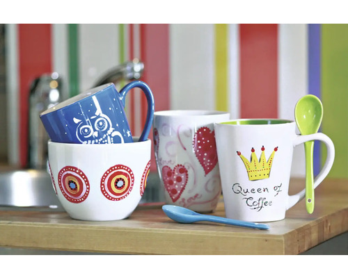 Diverse căni de cafea cu motive pe o masă de bucătărie.