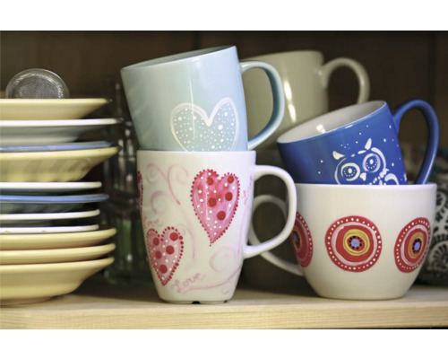 Stivă de căni ceramice cu diverse decorațiuni și farfurii pe raft.