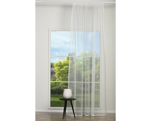 Fereastră cu perdea albă transparentă și măsuță laterală cu decorațiuni