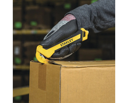 Mână cu mănușă de protecție care deschide o cutie de carton cu un tăietor rotativ Stanley