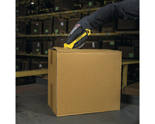 O persoană deschide o cutie de carton cu un cuțit Stanley într-un depozit.