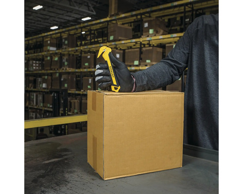 Logo Stanley. Deschizător de cutii cu lamă pe o cutie de carton într-un depozit.