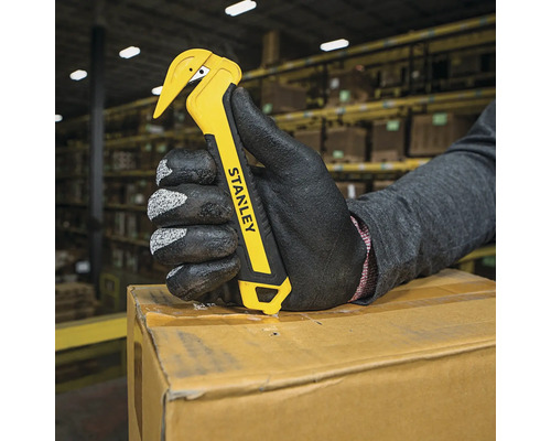 O mână cu mănușă deschide o cutie cu un cuțit Stanley galben.