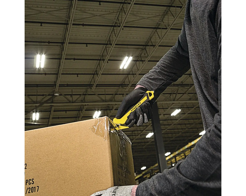 O persoană deschide o cutie de carton cu un cuțit Stanley galben.