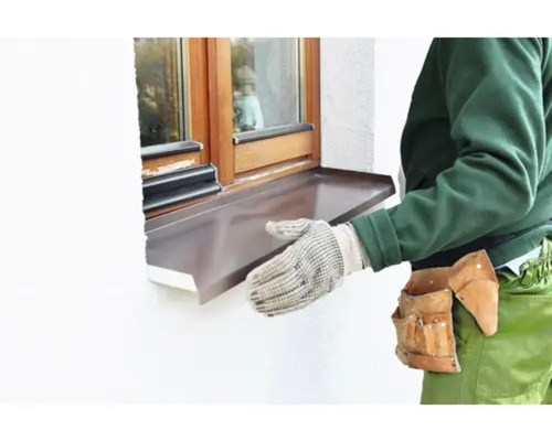 Artizan care montează o pervază metalică la o fereastră