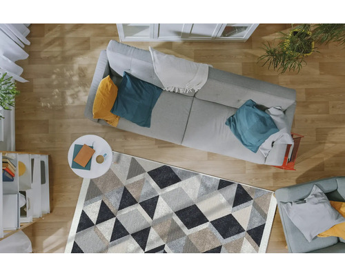 Vedere de sus a unui living cu canapea, măsuță de cafea și covor cu model geometric