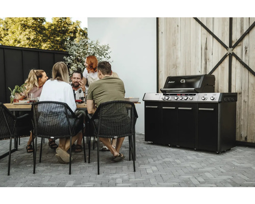 Grup de persoane stă la masă lângă un grătar pe gaz Enders pe o terasă.