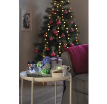 Scenă decorativă de Crăciun cu o pârtie de schi iluminată, o cană, un bol și un brad de Crăciun în fundal