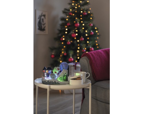 Scenă decorativă de Crăciun cu o pârtie de schi iluminată, o cană, un bol și un brad de Crăciun în fundal