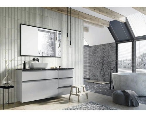 Baie luminoasă cu lavoar, oglindă, cadă și mozaic pe perete.