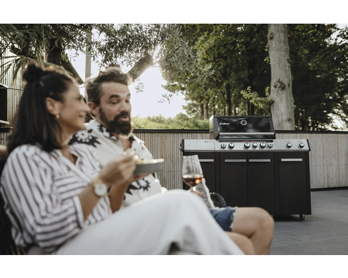 Scenă în aer liber cu un grătar pe gaz Enders, pe care un cuplu stă relaxat și mănâncă