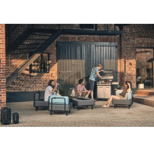 Grup de prieteni care fac grătar afară cu mobilier de grădină și un grătar