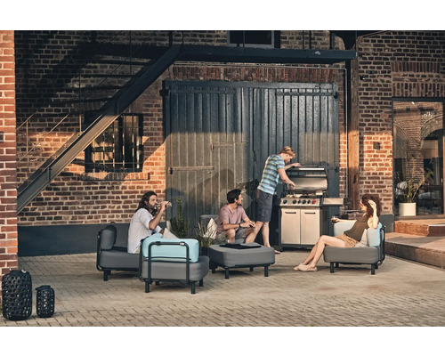 Grup de prieteni care fac grătar afară cu mobilier de grădină și un grătar