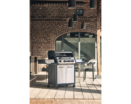 Grătar cu gaz pe o terasă cu un zid de piatră în fundal