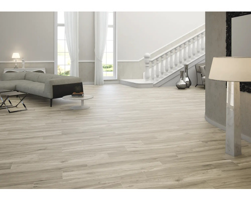 Cameră de zi luminoasă cu canapea, scară și gresie cu aspect de lemn