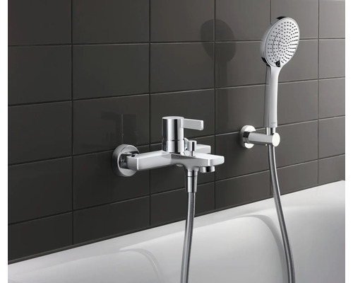 Baterie de baie aplicată cu duș de mână în fața unui fundal de faianță închisă la culoare