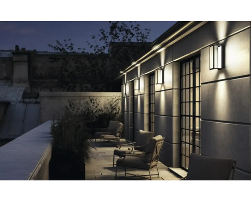 Zonă de terasă iluminată cu locuri de ședere și lămpi de perete exterioare pentru o ambianță plăcută.