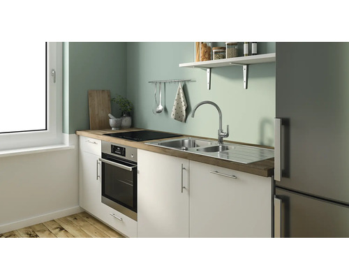 Scenă de bucătărie cu chiuvetă, plită, cuptor și frigider într-o aranjare luminoasă și organizată.