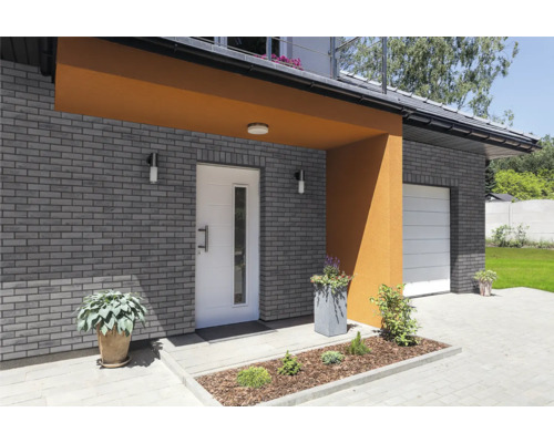 Fațadă de casă cu zidărie, ușă de intrare și ușă de garaj