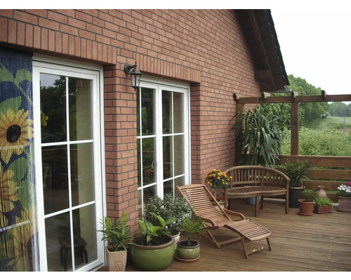 Vedere exterioară a unei case cu terasă, mobilier de grădină și plante