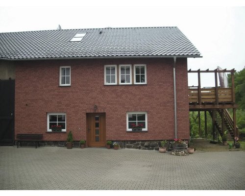 Vedere a unei case cu două etaje, cu acoperiș de țiglă și terasă din lemn