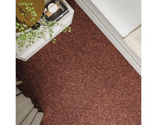 Prim-plan cu un covor cu model lângă un pat și o noptieră.