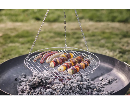 Grătar rotativ cu cârnați și frigărui de carne deasupra cărbunelui