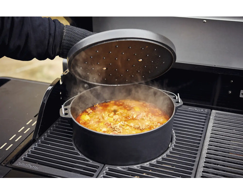 Oală cu capac pe un grătar cu mâncare înăuntru