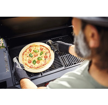 O pizza pe o piatră de pizza este preparată cu un grătar într-un grătar.