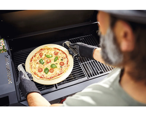 O pizza pe o piatră de pizza este preparată cu un grătar într-un grătar.