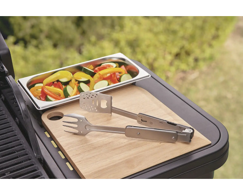 Legume într-un vas, clește pentru grătar și tocător pe un grătar