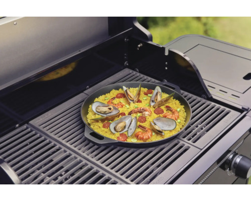 Paella cu fructe de mare preparată pe un grătar.