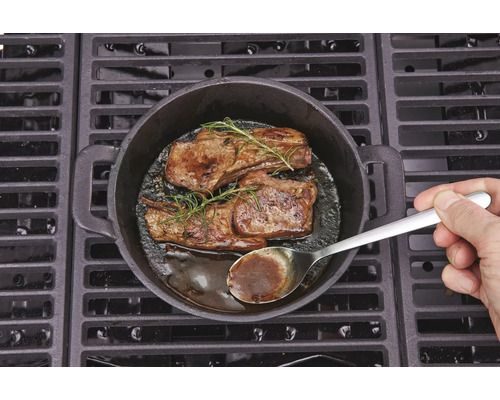 Două fripturi cu rozmarin preparate într-o tigaie de fontă pe un grătar