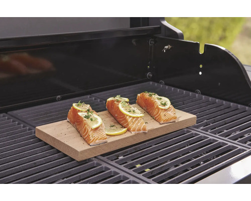 Trei fileuri de somon cu lămâie pe o scândură de lemn pe un grătar