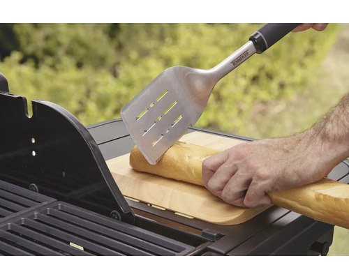O persoană taie o baghetă cu o spatulă de grătar pe un grătar.