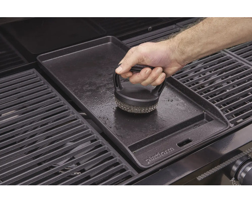 O placă de grătar este curățată cu o perie pentru grătar.