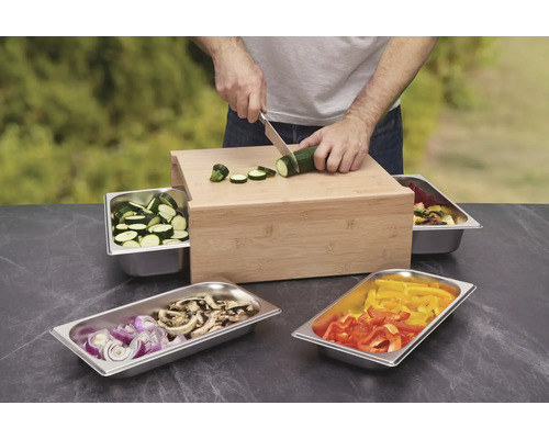 Tocător de legume din lemn cu recipiente și o persoană care taie legume