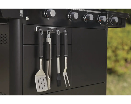 Prim-plan cu un grătar pe gaz negru cu ustensile pentru grătar