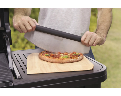 O persoană taie pizza cu un tăietor de pizza pe o planșetă de lemn.