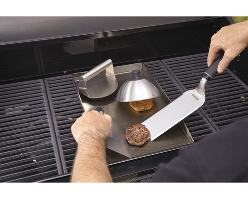 Prepararea hamburgerilor pe o plită cu presă de hamburgeri și spatulă