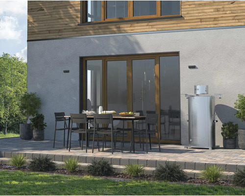 Terasa cu masă de grădină, scaune și încălzitor terasă în fața unei case.