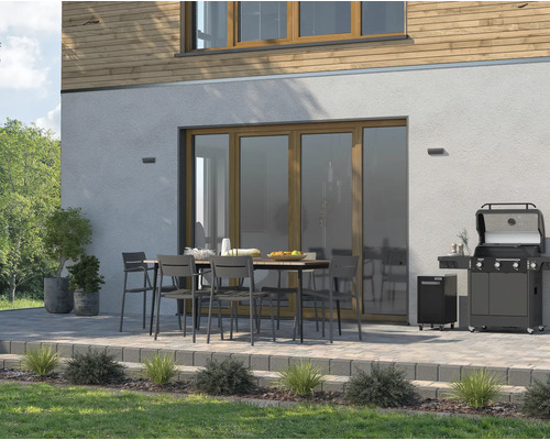 Terasa cu grătar pe gaz, masă de grădină și scaune în fața unei case