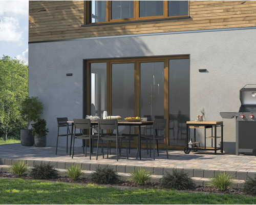 Terasa cu masă de sufragerie, scaune, grătar și cărucior pentru grătar în fața unei case