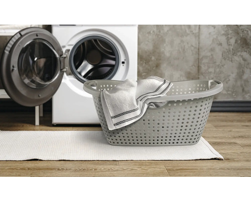 Coș de rufe cu rufe și mașină de spălat în fundal