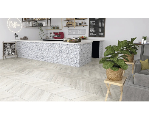 Fotografie de interior a unei cafenele cu podea din lemn în model herringbone, un tejghea cu plăci cu model și plante de interior