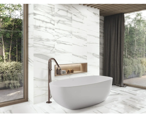 Baie modernă cu cadă freestanding, robinet și plăci de marmură.