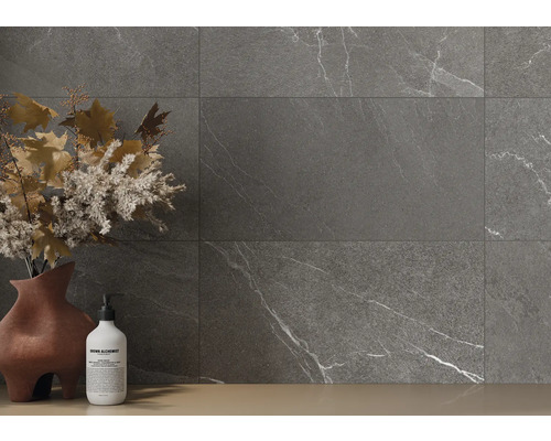 Plăci gri cu aspect de marmură pe un perete, completate de o vază cu decorațiuni florale și o sticlă de săpun