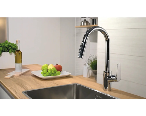 Scenă de bucătărie cu baterie de chiuvetă, chiuvetă și vas cu fructe pe un blat de lucru din lemn