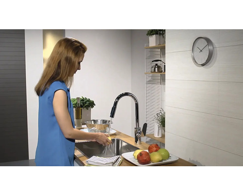 Femeie spală legume sub un robinet într-o bucătărie modernă