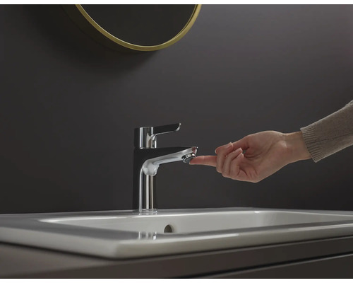 O mână acționează o baterie metalică pe o chiuvetă.